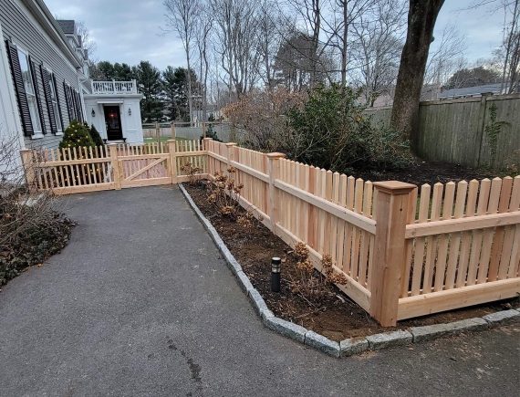 light natural wooden picket fence around a backyard