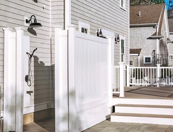 outdoor shower with white fence surround, paver patio